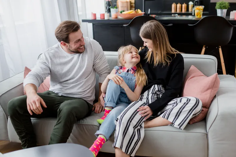 A couple and their daughter spending time together on the sofa at home