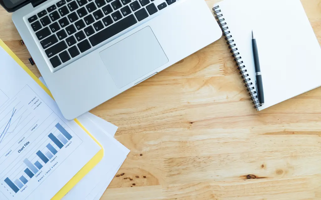 Cuaderno, ordenador y documentación contable sobre una mesa de trabajo