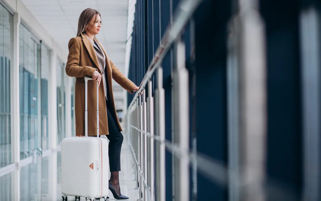 Viajera con equipaje junto a los ventanales de una terminal